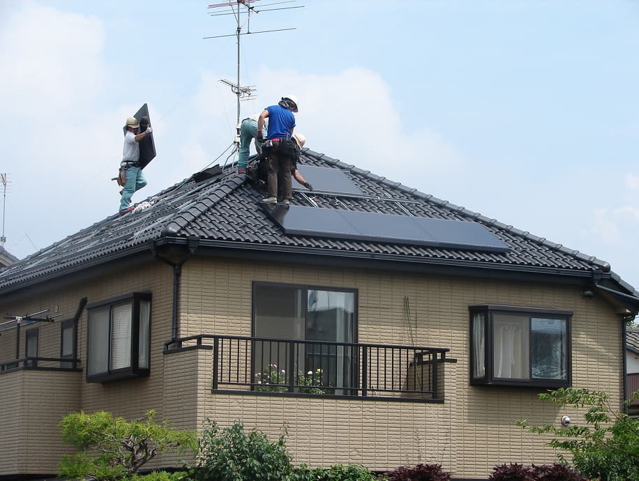 作業員が屋根に上って太陽光発電システムを設置している様子