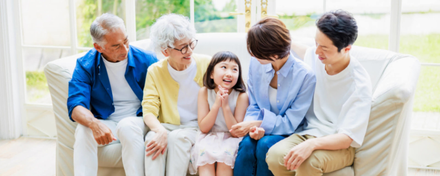 明るいリビングで3世代の家族が笑顔でお話をしている画像